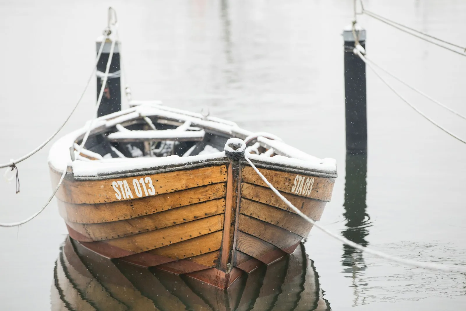 Gammel klinkbygd trebåt fortøyd i stille vann