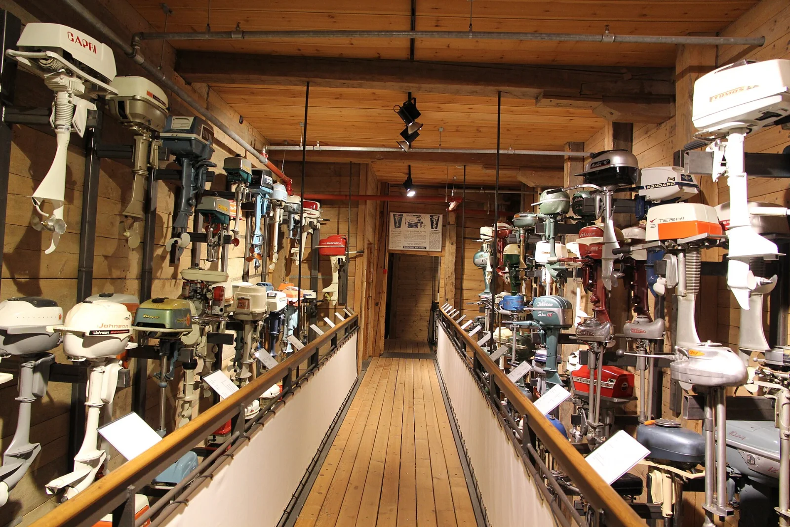 Lang rad med historiske påhengsmotorer utstilt i et maritimt museum